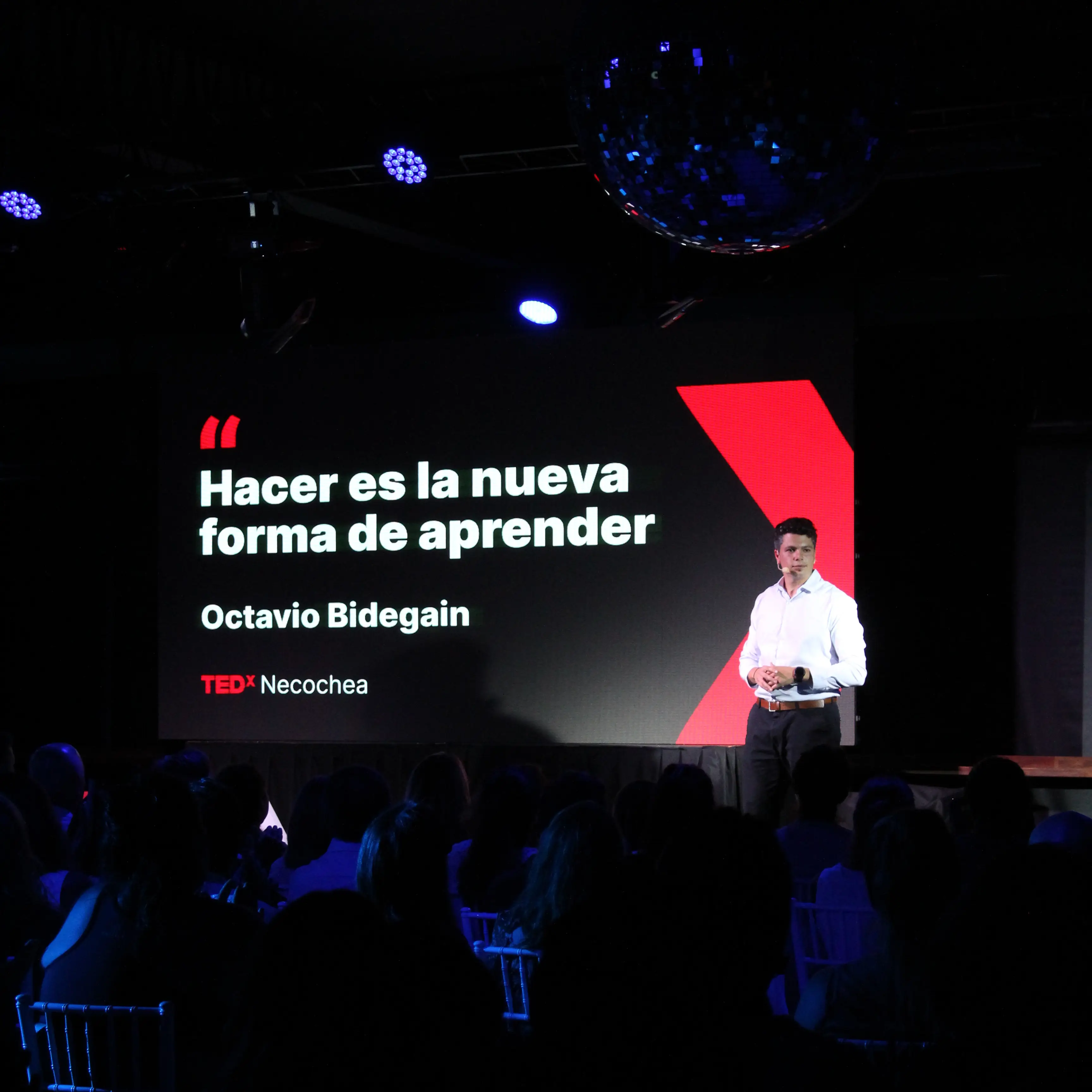 Escenario de TEDxNecochea con el título de la charla proyectado en pantalla